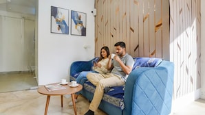 A modern living room with a blue sofa, a small wooden coffee table, and abstract art on the wall. - Fabhotel Beach Front Resort (Calangute)
