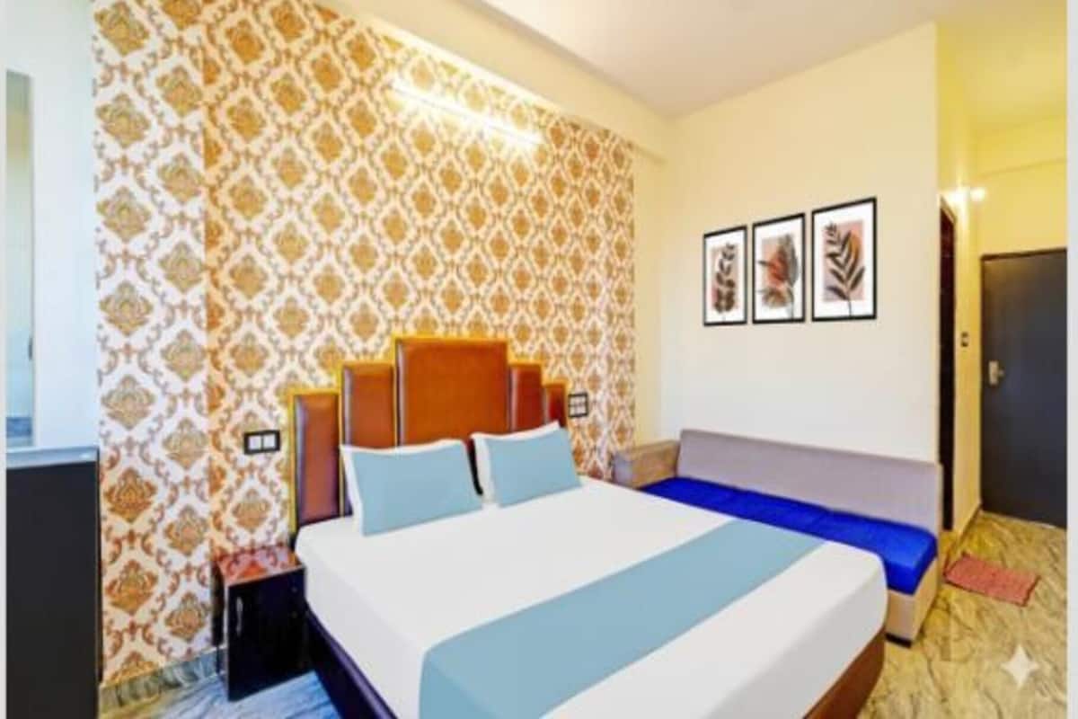 Een hotelkamer met een groot bed, een slaapbank, behang met een patroon en lijstwerken aan de muur.