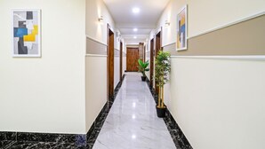 A hallway with marble flooring, wooden doors, and potted plants. - Fabhotel Melody Nx (Thane)