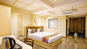 A hotel room with a large bed, a desk with a kettle, and a chair. - Fabhotel Melody Nx (Thane)