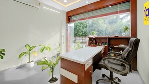A modern office space with a white desk, black office chair, and potted plants. - Fabhotel Shri Vinayak (Bhopal)