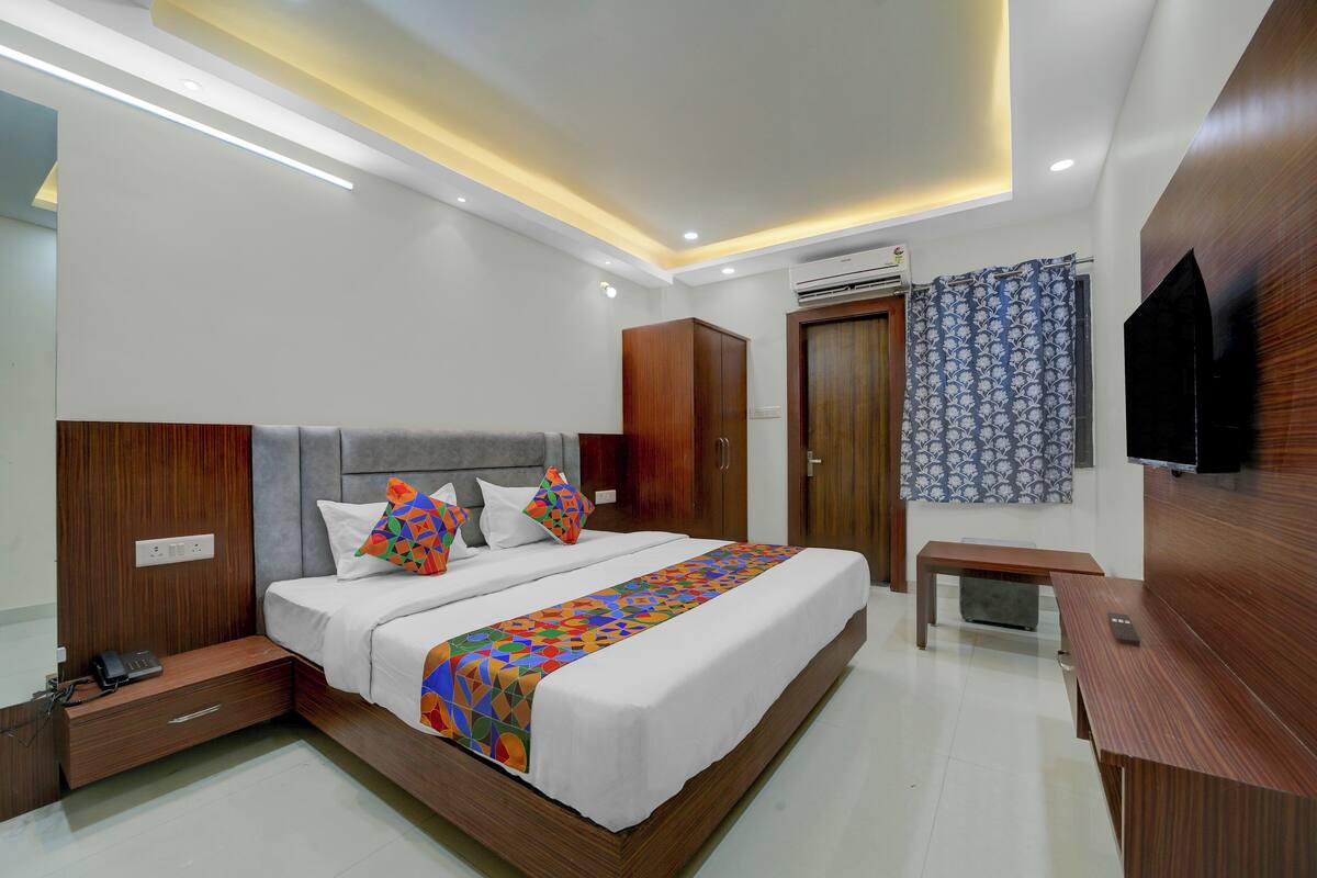 A modern bedroom with a large bed, wooden headboard, bedside tables, and a built-in TV.