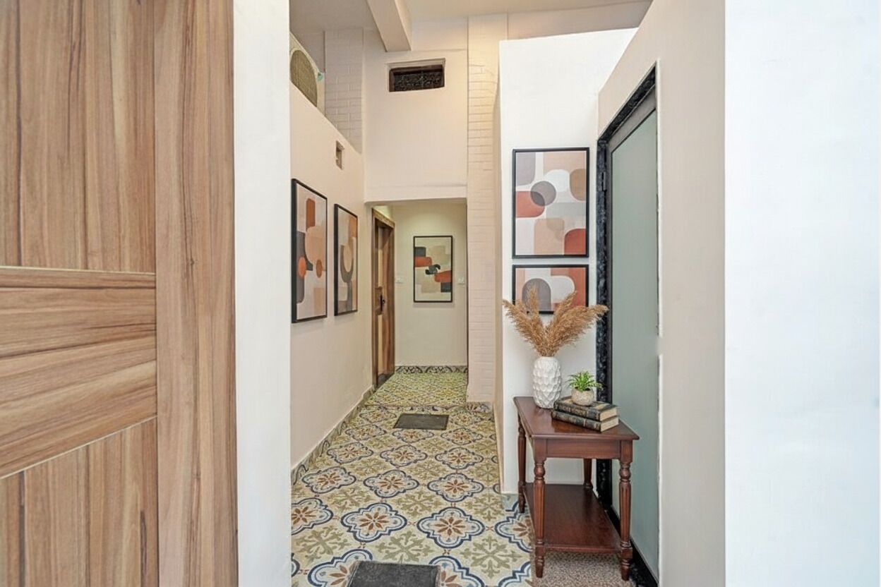 Un couloir doté d’un sol à motifs, de tableaux encadrés accrochés aux murs et d’une petite table ornée d’objets décoratifs.