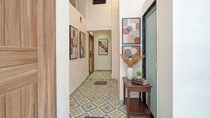Un couloir doté d’un sol à motifs, de tableaux encadrés accrochés aux murs et d’une petite table ornée d’objets décoratifs.
