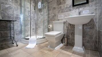 A modern bathroom with a glass-enclosed shower, a toilet, and a pedestal sink.