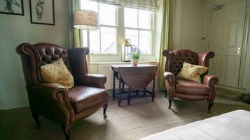 A room with two leather armchairs, a small table with a lamp, and a window with curtains.