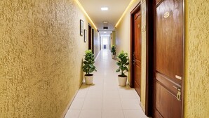 Un pasillo con plantas en macetas, puertas de madera y suelo de baldosas.