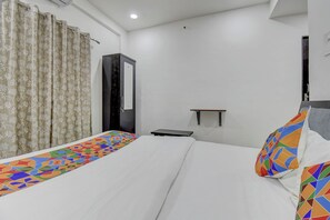 A hotel room with a bed, a wardrobe, a bedside table, and a small shelf. - Fabhotel Spark Inn (Pune)