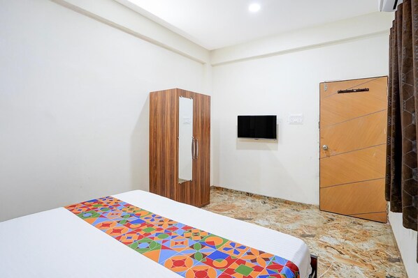 A small, clean room with a bed, a wardrobe, and a television. - Fabhotel Sp 97 (Indore)