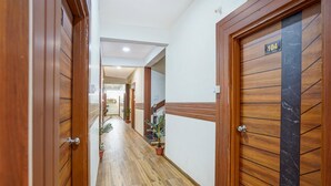 A hallway with wooden doors, some with marble panels, and potted plants along the floor. - Fabhotel Sp 97 (Indore)