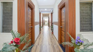 A hotel hallway with wooden doors, potted plants, and a tiled floor. - Fabhotel Sp 97 (Indore)
