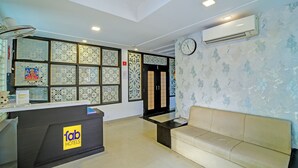 Un espace d’accueil d’hôtel comprenant un comptoir de réception, une horloge et un canapé.