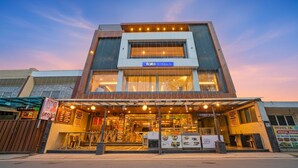 Un bâtiment moderne, orné d'une enseigne « fabHOTELS », avec une grande vitrine et un espace extérieur aménagé avec des places assises couvertes.