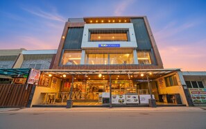 Un bâtiment moderne, orné d'une enseigne « fabHOTELS », avec une grande vitrine et un espace extérieur aménagé avec des places assises couvertes.