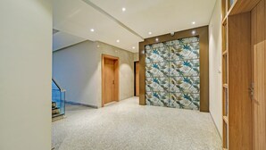 A hallway with a tiled floor, wooden doors, and a decorative glass partition. - Fabhotel Shri Shreeyam Stay (Bhopal)
