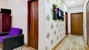 A hallway with a sofa, a television, and a wall decorated with a floral arrangement. - Fabhotel A2 (Barasat)