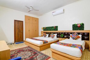 A hotel room with two beds, a wardrobe, a ceiling fan, an air conditioning unit, and decorative wall plants. - Fabhotel A2 (Barasat)