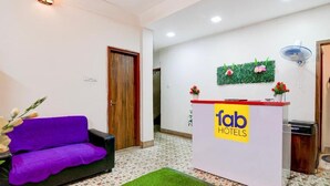 A reception area with a purple sofa, a reception desk labeled 'fab hotels', and a green wall decoration. - Fabhotel A2 (Barasat)