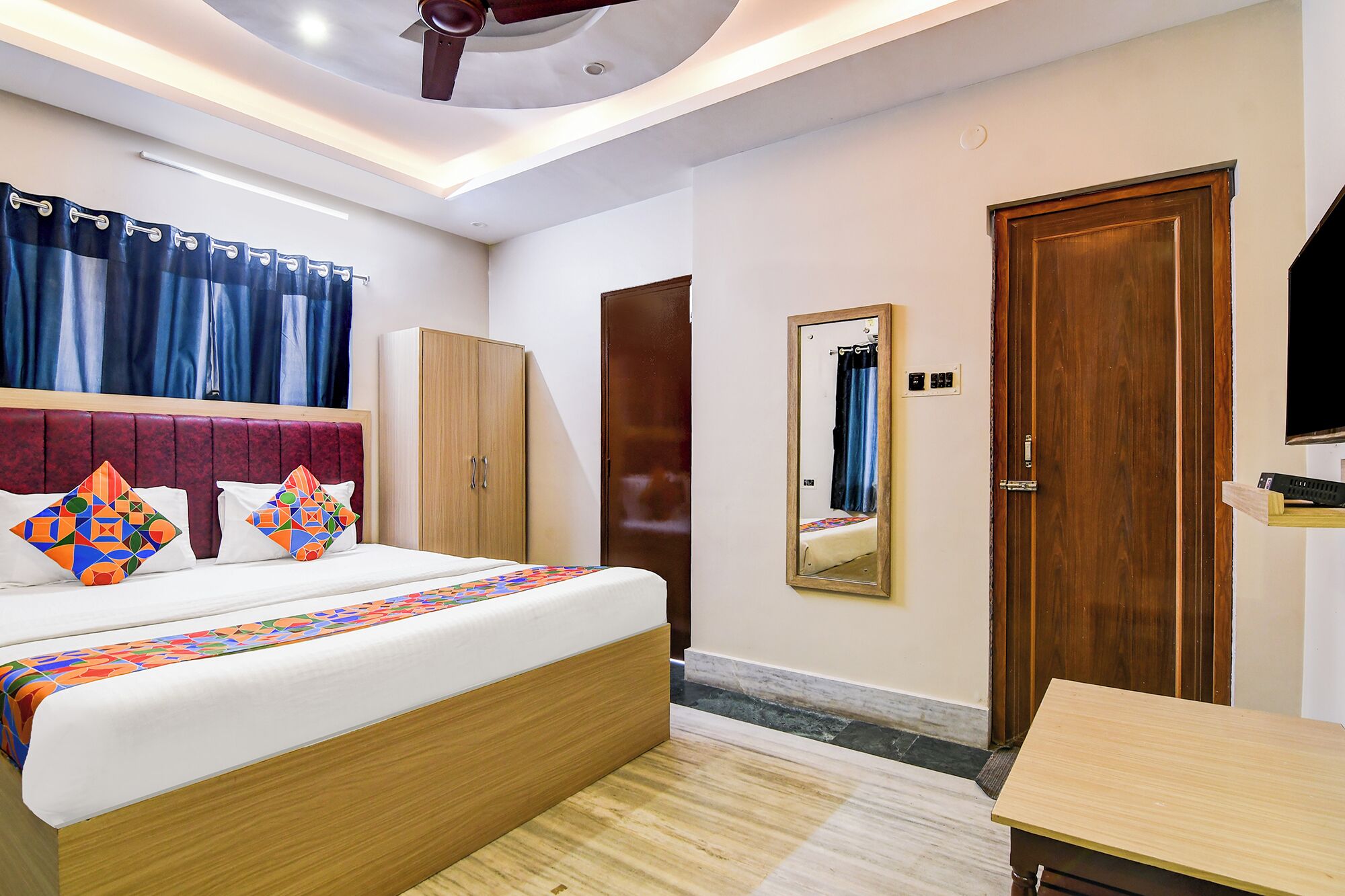A bedroom with a bed, wardrobe, mirror, and a small table.