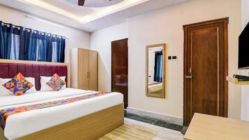 A bedroom with a bed, wardrobe, mirror, and a small table.
