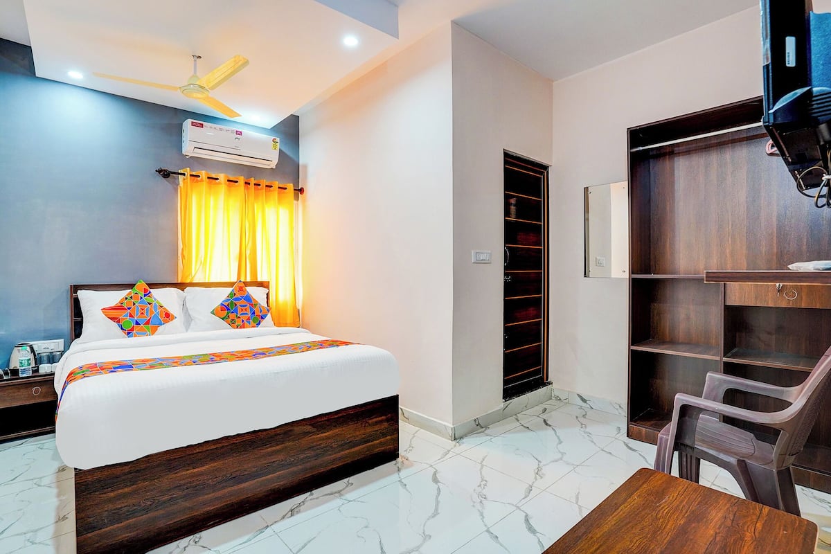 Une chambre d’hôtel équipée d’un lit, d’un bureau, d’une chaise, d’une armoire et d’un ventilateur de plafond.