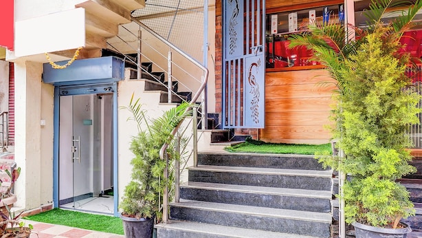 A building entrance with a staircase, a blue door, and potted plants. - FabHotel Aranya Residency - HSR Layout (Bengaluru)