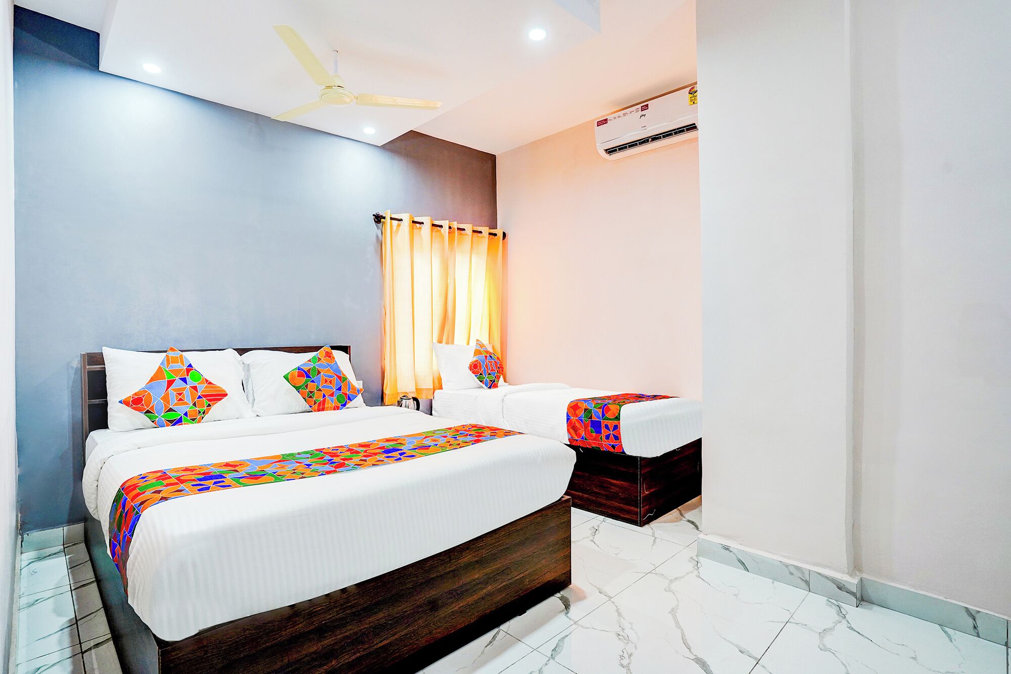 A hotel room with a bed, two bedside tables, a ceiling fan, and an air conditioning unit.