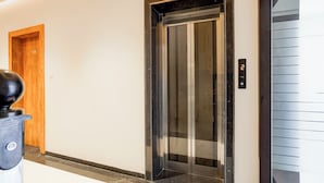 An elevator with a digital display, a wooden door, and a marble floor. - Fabhotel Cosmos Green (Indore)