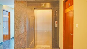 An elevator with a marble wall and a wooden door to the right. - FabHotel New Mysore Gate (Bengaluru)