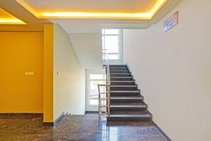 A modern hotel interior with a marble staircase, a bright yellow wall, and a sign indicating the 4th floor. - FabHotel New Mysore Gate (Bengaluru)