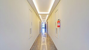 A long, well-lit hallway with a fire extinguisher mounted on the wall. - FabHotel New Mysore Gate (Bengaluru)