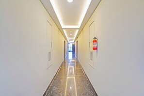 A long, well-lit hallway with a fire extinguisher mounted on the wall. - FabHotel New Mysore Gate (Bengaluru)