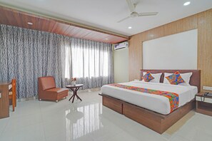 A hotel room with a large bed, a wooden headboard, a ceiling fan, and a window with patterned curtains. - FabHotel New Mysore Gate (Bengaluru)