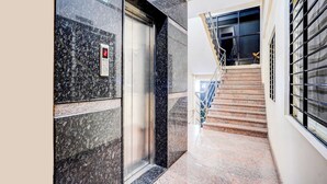 An elevator with a digital display, a stairwell with metal railings, and a sign indicating the use of stairs. - Fabhotel Pride Image (Bangalore)