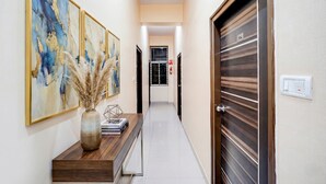 A hallway with a wooden console table, a vase with dried plants, and framed artwork on the wall. - Fabhotel Pride Image (Bangalore)
