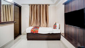 A bedroom with a bed, a TV, and a window with curtains. - Fabhotel Pride Image (Bangalore)