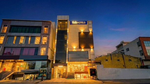 A modern hotel with a prominent 'fab hotels' sign, featuring a central staircase and a glass facade. - Fabhotel Pride Image (Bangalore)