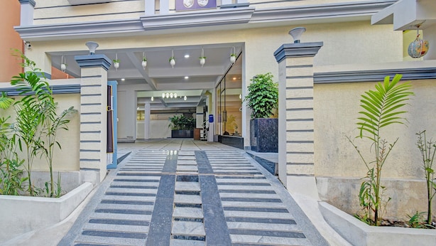 A hotel entrance with a modern design, featuring a central staircase leading to the entrance, flanked by potted plants and a signboard above. - Fabhotel Broholic Stay Inn (Hyderabad)