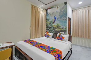 Habitación de hotel con cama, cortinas color beige, un mural de pavo real y una colcha blanca.