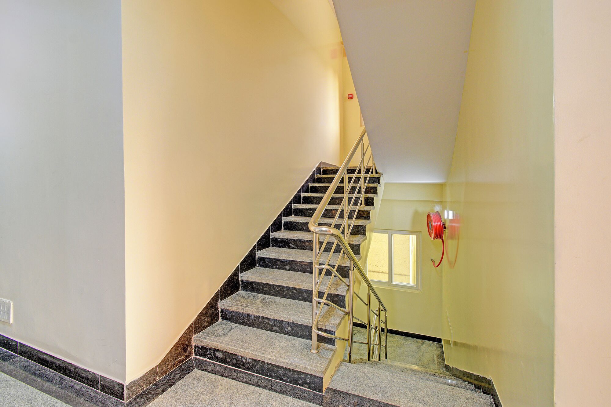 A staircase with a handrail and a fire hose reel on the wall.