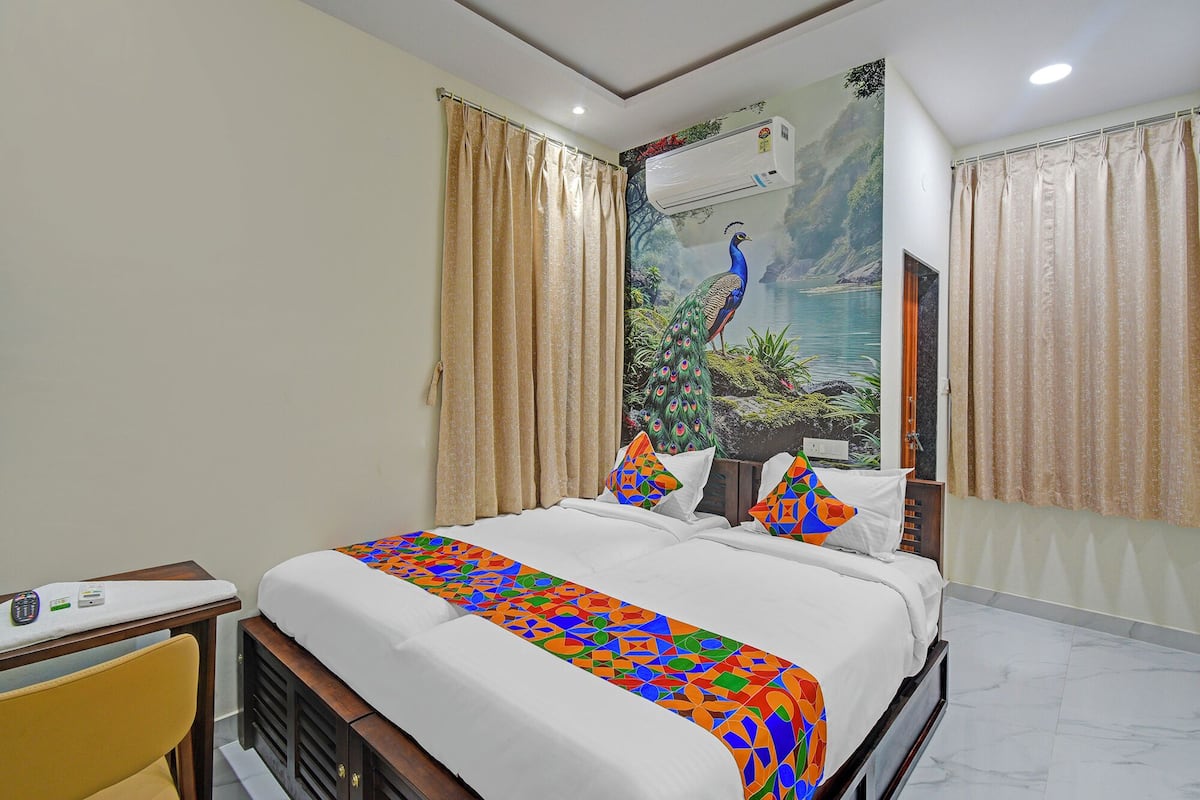 A hotel room with a bed, beige curtains, a peacock mural, and a marble floor.