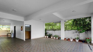 A spacious indoor area with a patterned floor, white walls, and a garden view. - Fabhotel Pavis Inn (Chennai)