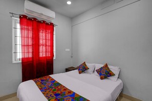A bedroom with a bed, two pillows, a red curtain, and an air conditioning unit. - Fabhotel Pavis Inn (Chennai)