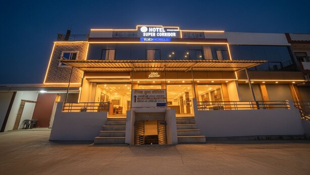 Un hotel moderno con una entrada destacada, un área cubierta y un letrero que indica que es un 'Hotel Super Corridor' de FabHotels.
