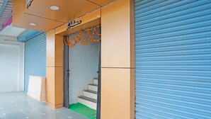 Tienda cerrada con un cartel que dice 'Welcome' sobre la entrada, una escalera que lleva al interior y una puerta con persiana azul a la derecha.