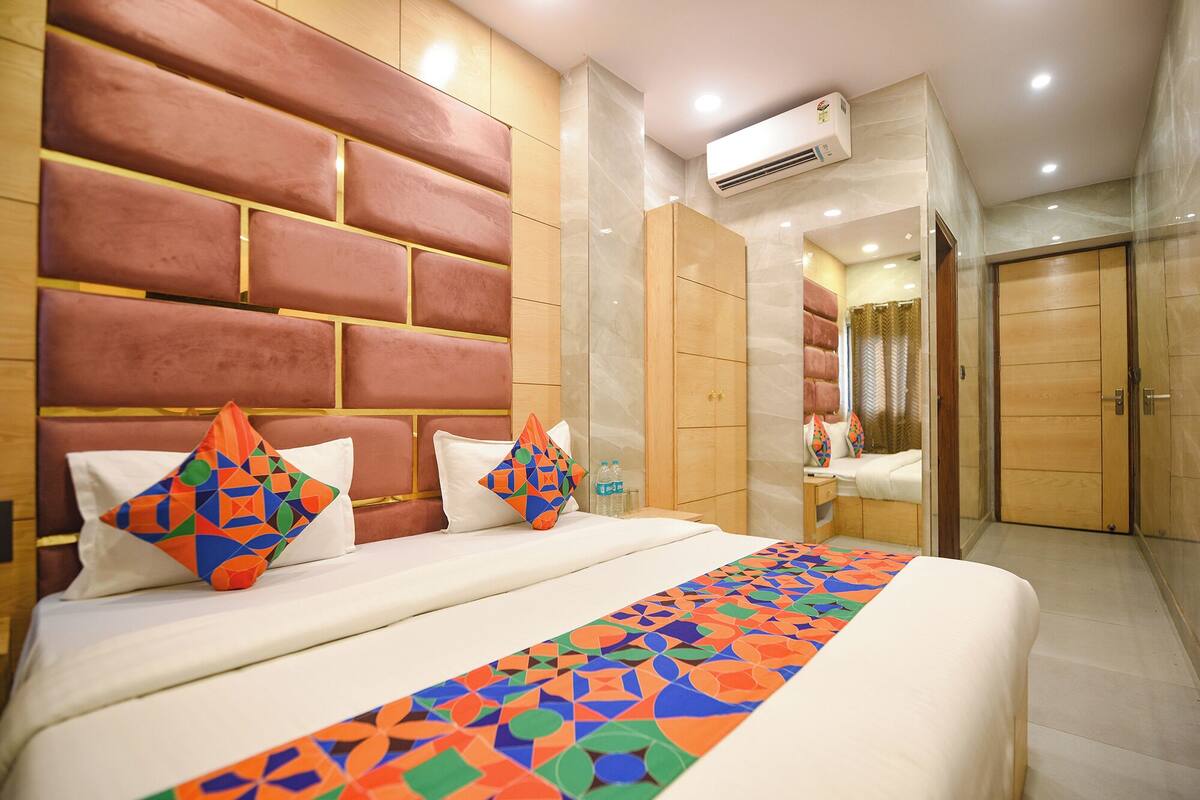 Una habitación de hotel con una cama grande, una colcha de diseño geométrico y un cabecero con estampado de ladrillo.