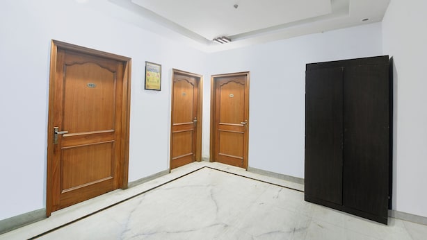 Un couloir avec trois portes en bois, chacune portant un numéro, qui donnent accès à des pièces.