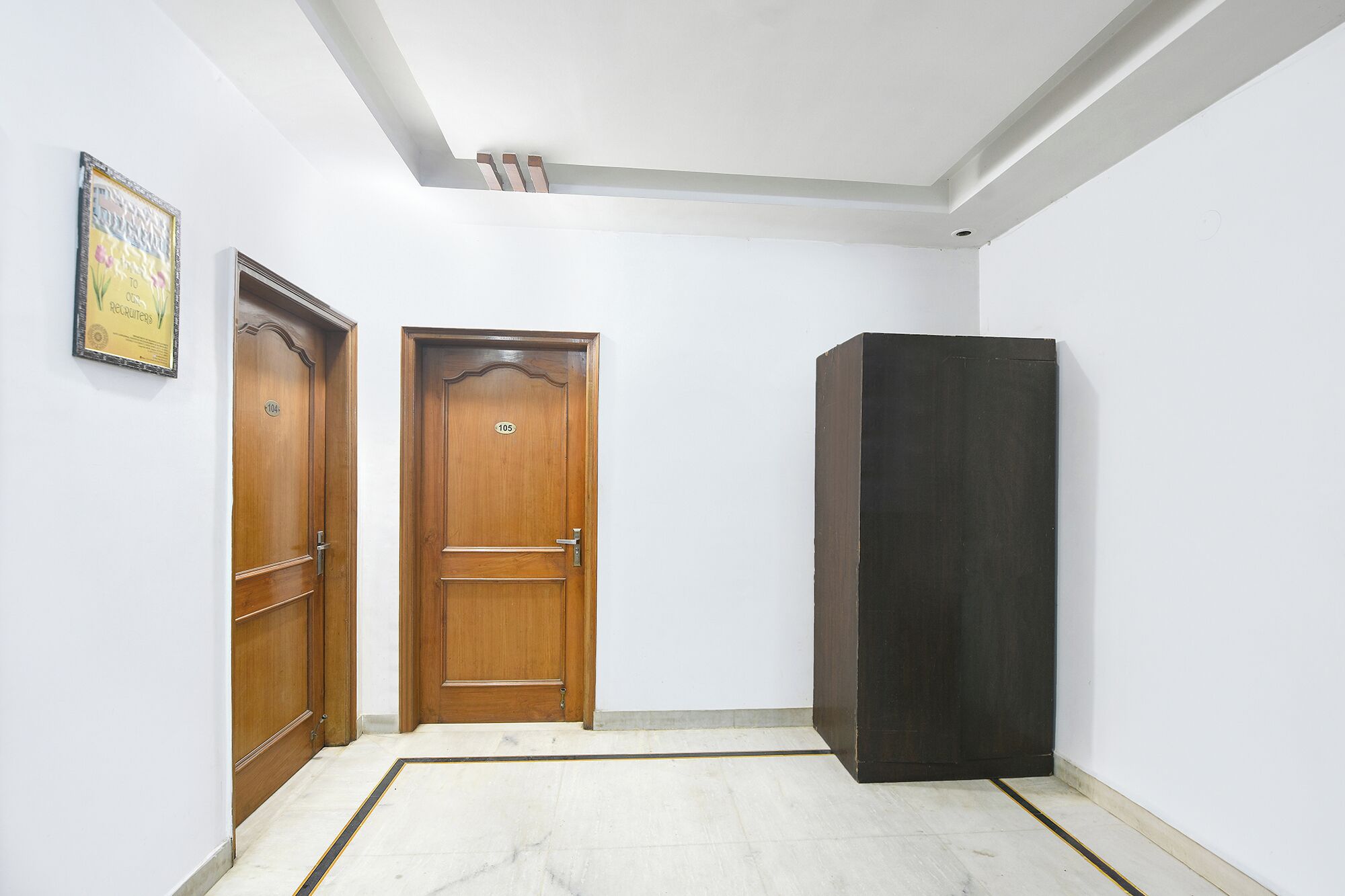 A hallway with two wooden doors, one labeled 104 and the other 105, and a dark-colored cabinet.
