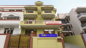 Un hôtel à plusieurs étages, avec une enseigne indiquant « Hôtel Vagmi Paradise (séjour de luxe et confortable) » et une autre enseigne « Tab Hotels ».