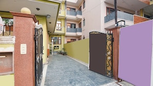 Une ruelle étroite, avec une entrée fermée par un portail, un petit panneau indicateur et un immeuble doté d’un balcon.